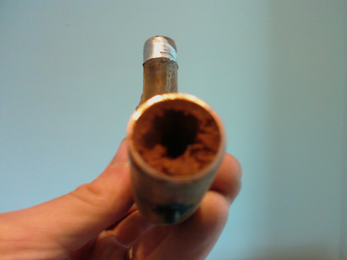 A cut section of heating pipe, almost completely blocked with black sludge